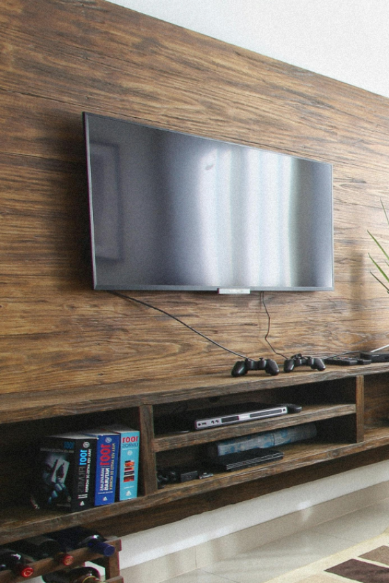 TV mounted above a white brick fireplace on a wood panel wall