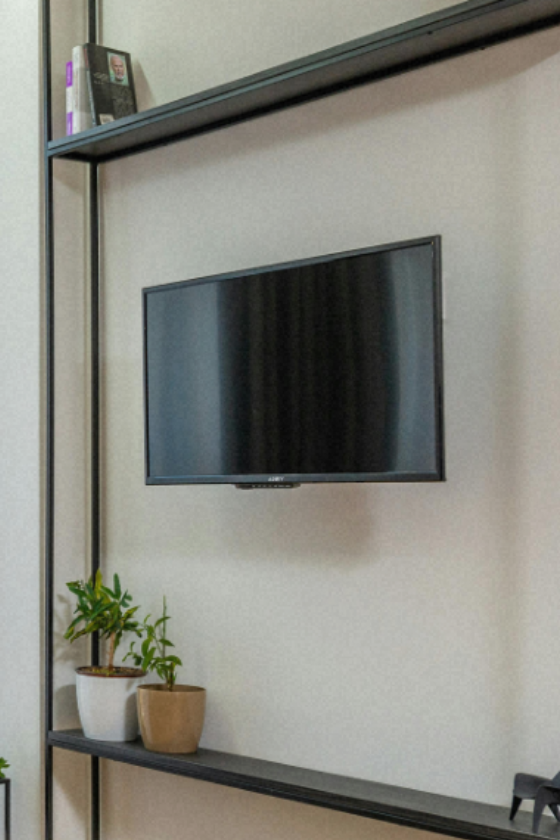 TV mounted on a light wall above a rustic cabinet